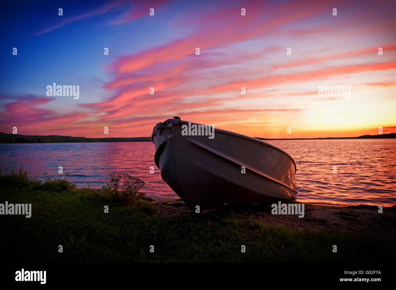 Bild von Fischerboot am Ufer des Sees bei Sonnenuntergang Stockfoto