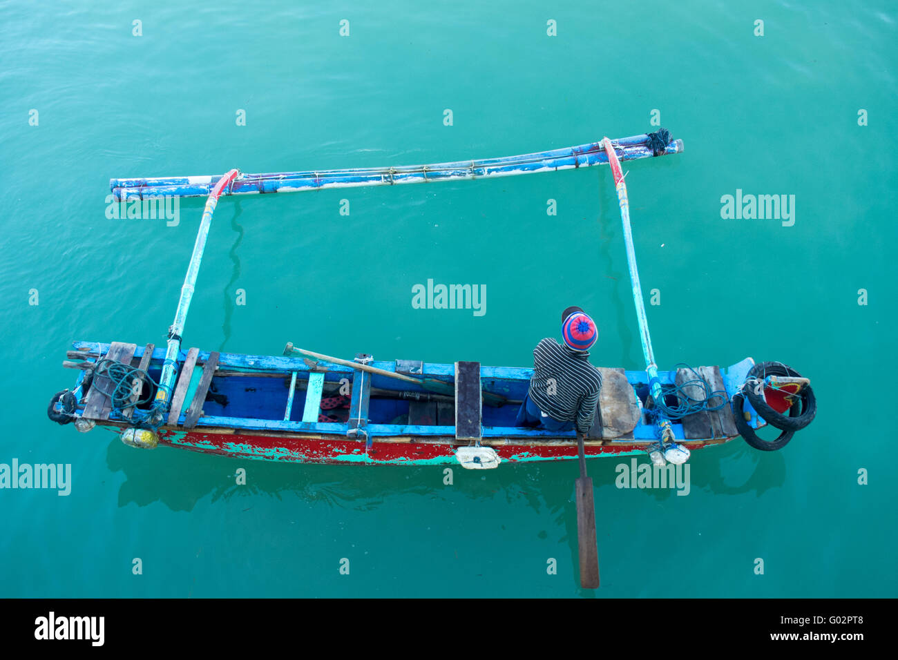Ein Fischer paddeln in einer Jukung oder einem traditionellen Holzboot in Jimbaran Bay, Bali. Stockfoto