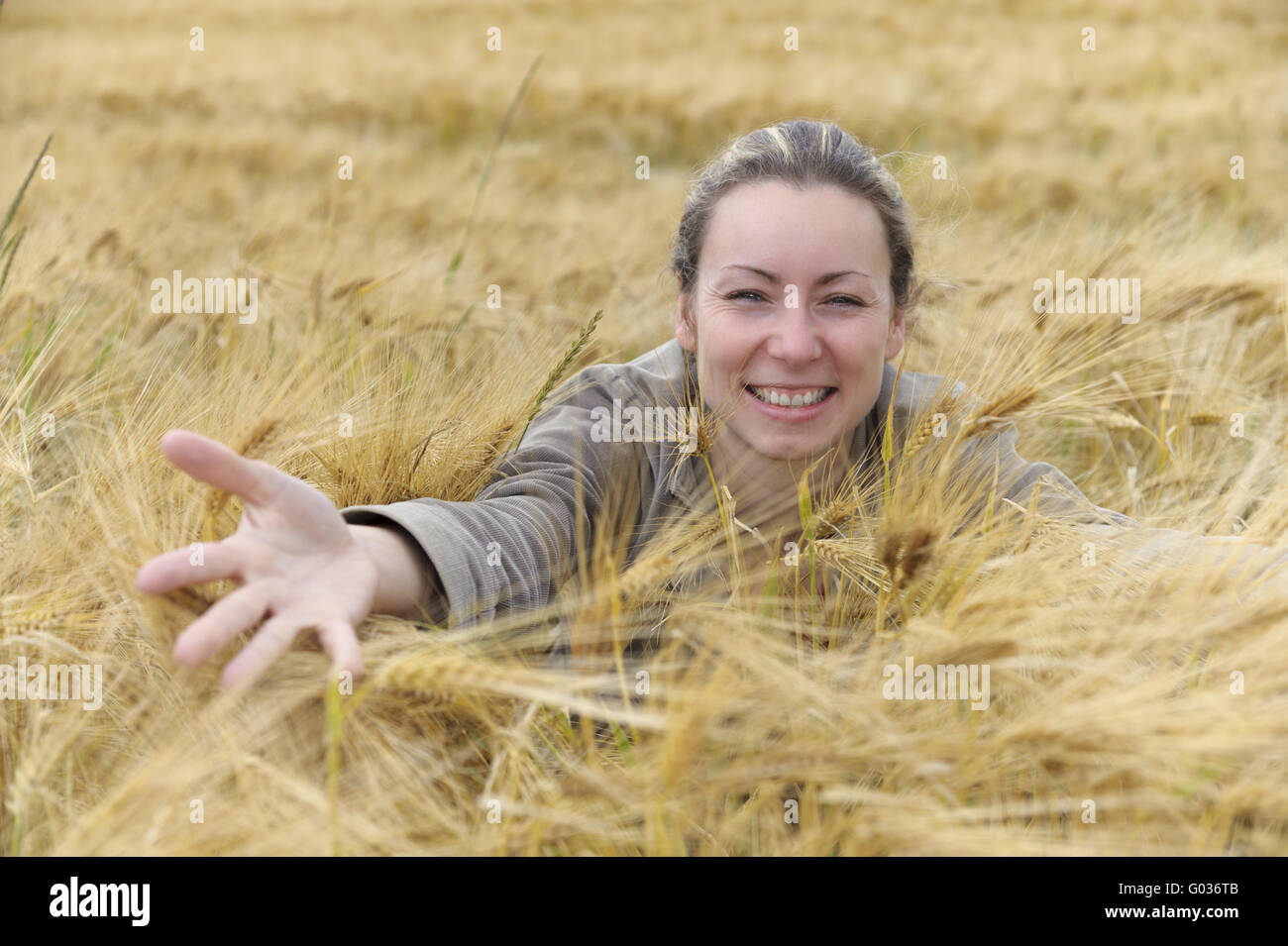 junge Frau in einem Kornfeld mit ausgestreckter hand Stockfoto