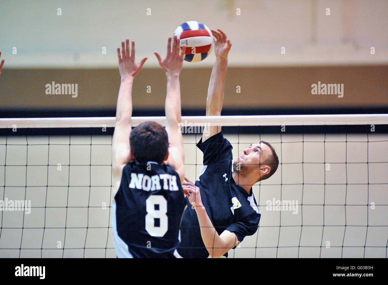 High School Spieler versucht, einen Volley mit einer Tötung Schuß über eine Sperrminorität Bemühen eines Gegners zu beenden. USA. Stockfoto