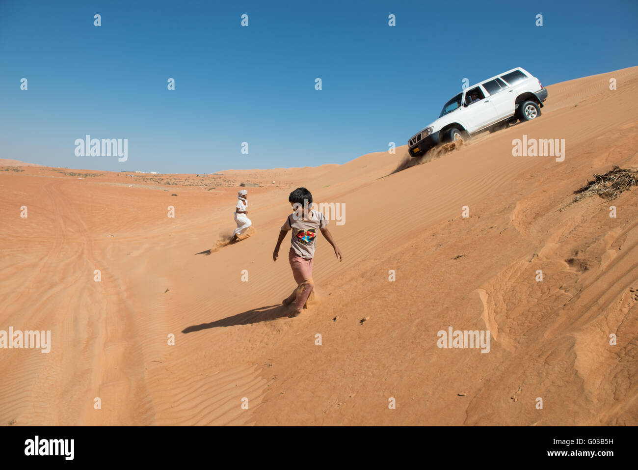 Omanische Jugend spielen in Sanddünen. Stockfoto