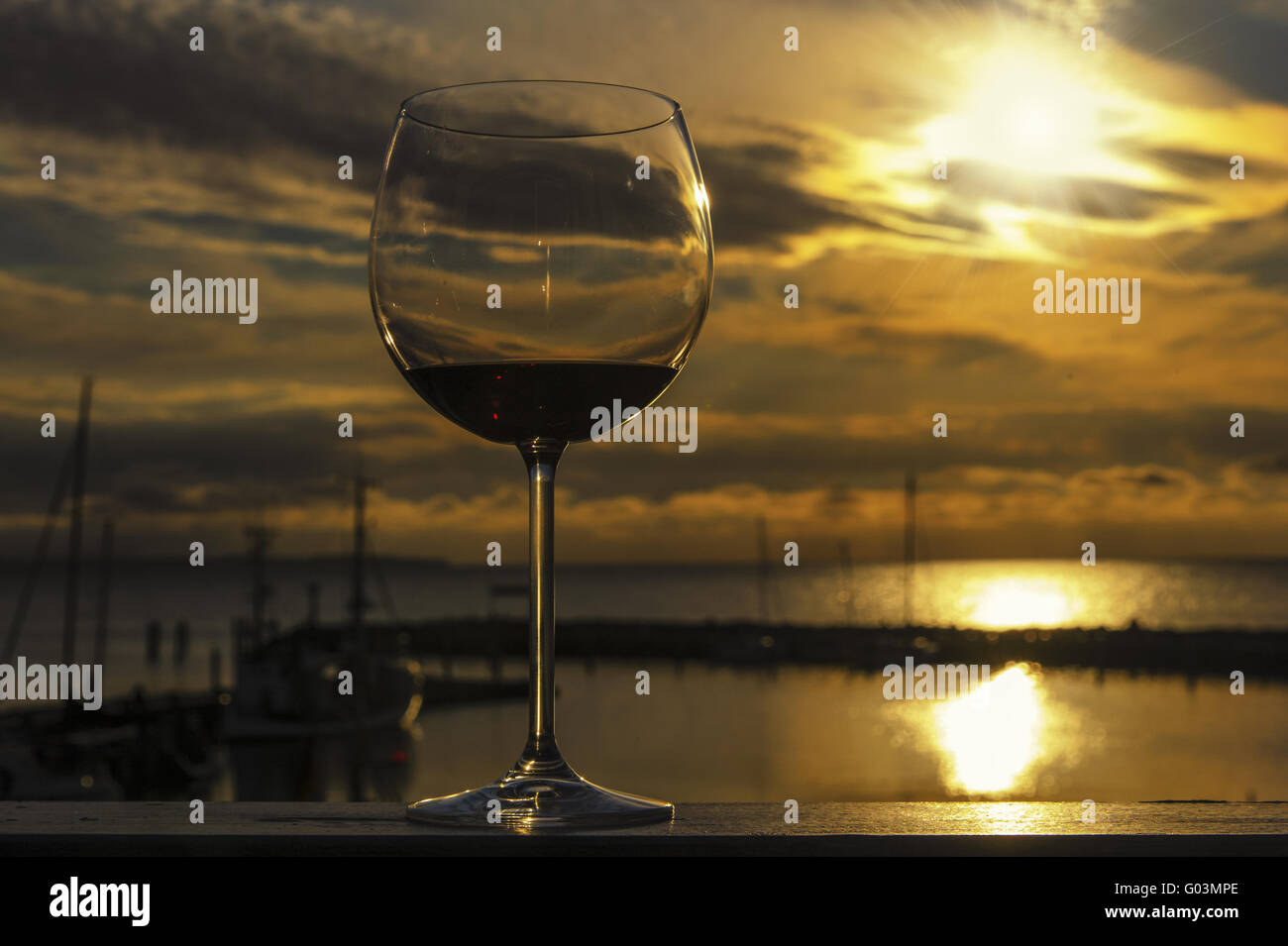 ein Glas Rotwein ist auf der Brüstung eines Balkons Stockfoto
