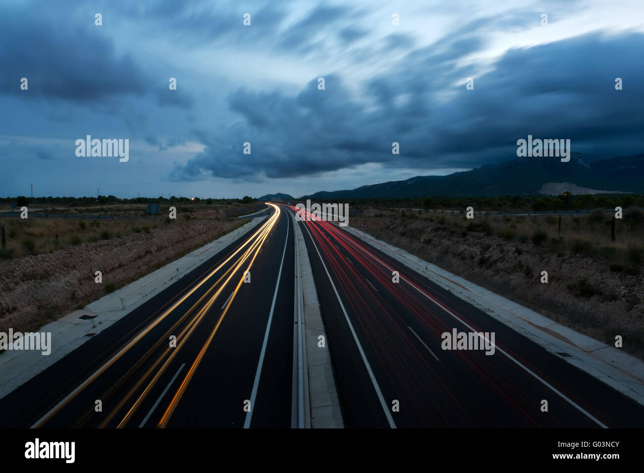 Autobahn mit Spuren von Autoscheinwerfer in der Dämmerung Stockfoto