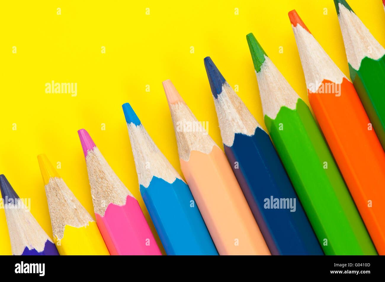 Bunte Bleistifte hautnah auf leuchtend gelbem Hintergrund Stockfoto