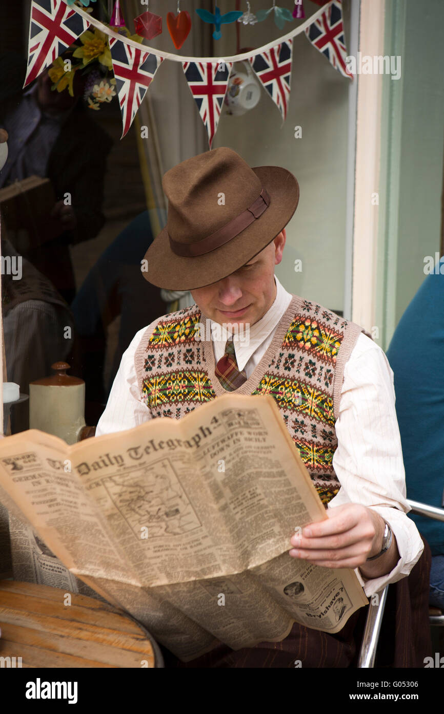 Großbritannien, England, Yorkshire, Haworth 40er Jahre Wochenende, Main Street, Andy Hart lesen während des Krieges Daily Telegraph Stockfoto