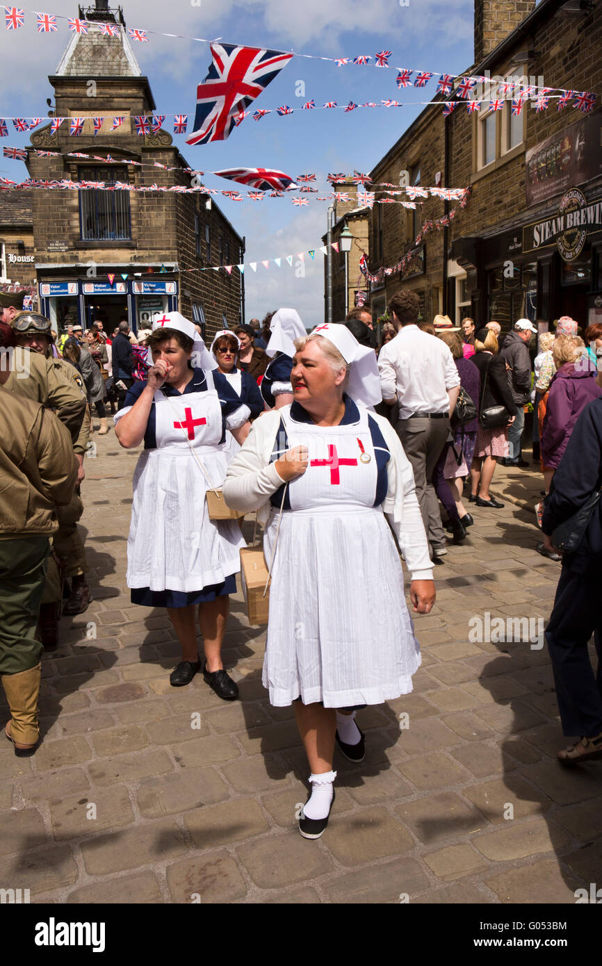 Großbritannien, England, Yorkshire, Haworth 40er Jahre Wochenende, Gruppe von Krankenschwestern gepflasterten Hauptstraße hinunter Stockfoto