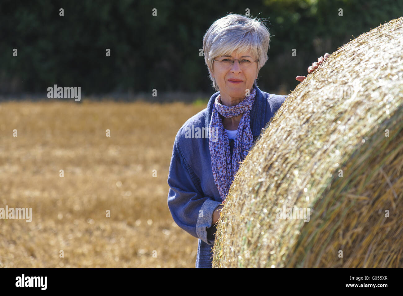 Ältere Frau steht auf einem Maisfeld hinter einem stra Stockfoto