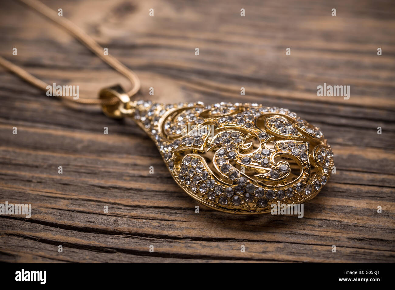 Vergoldete Anhänger mit Steinchen auf hölzernen Hintergrund Stockfoto