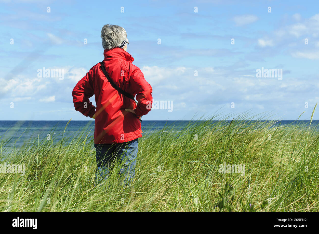 eine Frau steht in den Dünen und befasst sich mit der Stockfoto