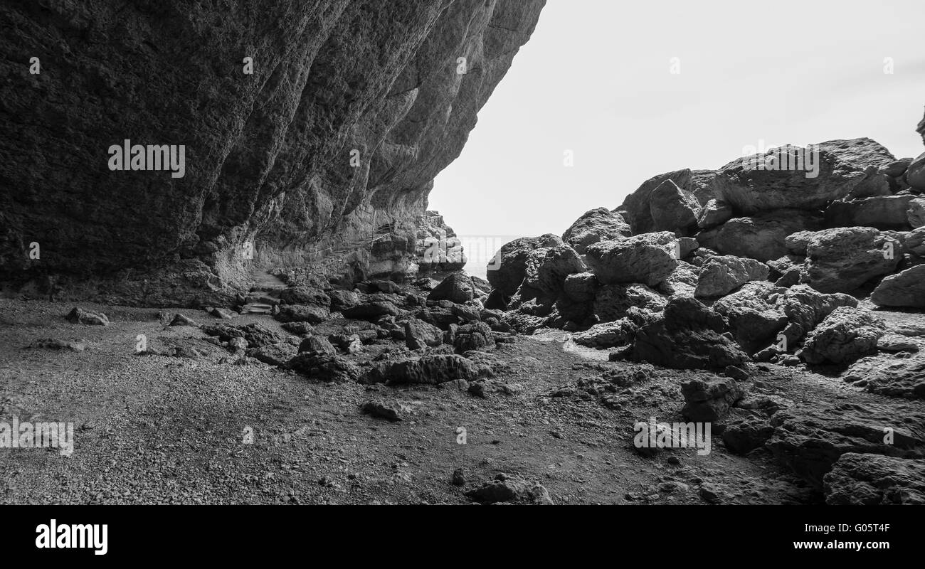 Einsame Bucht mit riesigen Küstenfelsen, schwarz / weiß Foto Stockfoto