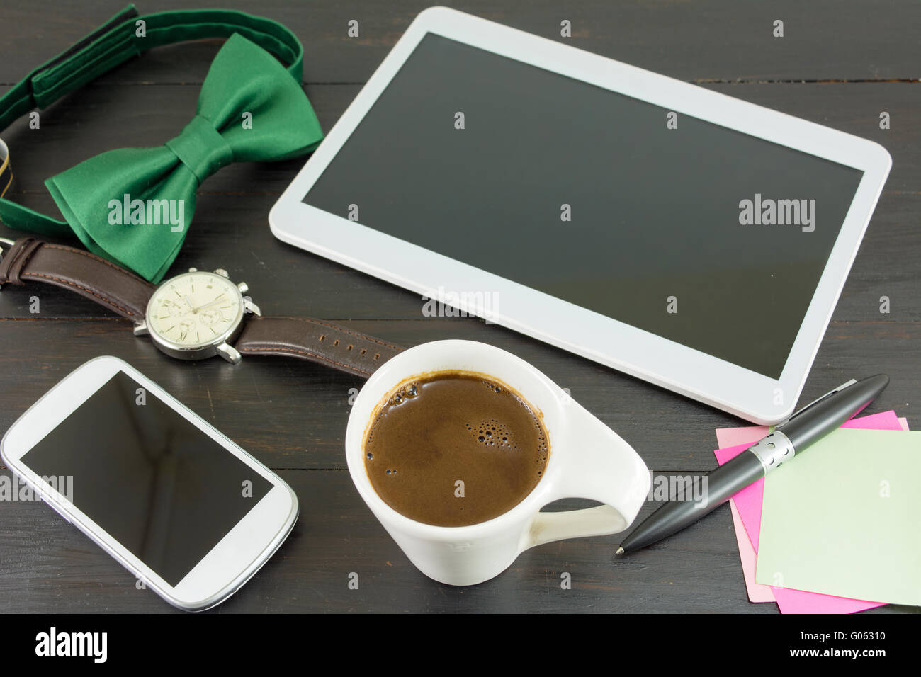 Tasse Kaffee für einen guten Arbeitstag. Kaffee und Tech Zubehör am schwarzen Tisch Stockfoto