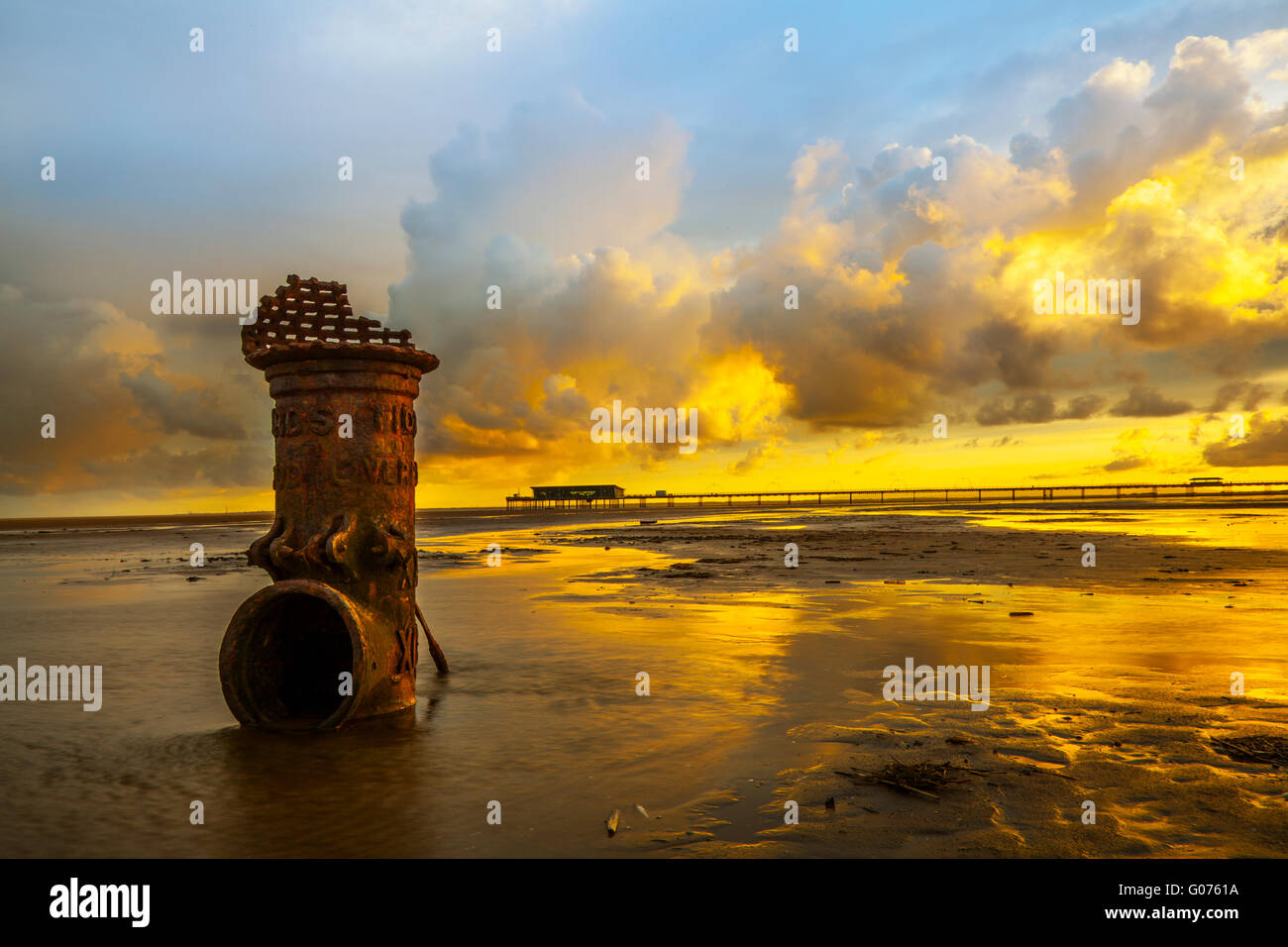 Farbenprächtiger Sonnenaufgang über der Irischen See, der den Liverpool Fleetwood Victorian Cast Iron Tidal Standard bei Niedrigwasser beleuchtet. Die römischen Ziffern deuten darauf hin, dass es sich um die Tiefzugsmarken eines Schiffes in vergangenen Zeiten handelt, die einen Kanal für den Zugang zum nun nicht mehr existierenden und verschlammten Hafen markieren. Southport, Merseyside, Stockfoto