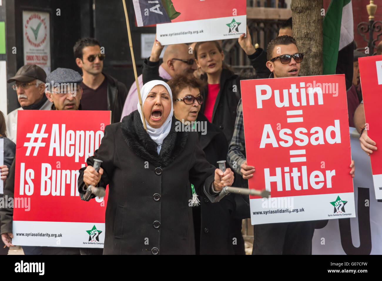 London, UK. 30. April 2016. Demonstranten in der Nähe der russischen Botschaft forderten ein Ende der russischen und syrische Luftangriffe auf Aleppo nach ein Überfall auf das Al-Qudus Krankenhaus letzte Mittwoch Nacht Zehntausende Zivilisten, einschließlich Kinder und drei Ärzte getötet. Eine Frau winkt ihre Krücken aus Protest zwischen Poster "#Aleppo brennt" und "Putin = Assad = Hitler". Peter Marshall/Alamy Live-Nachrichten Stockfoto