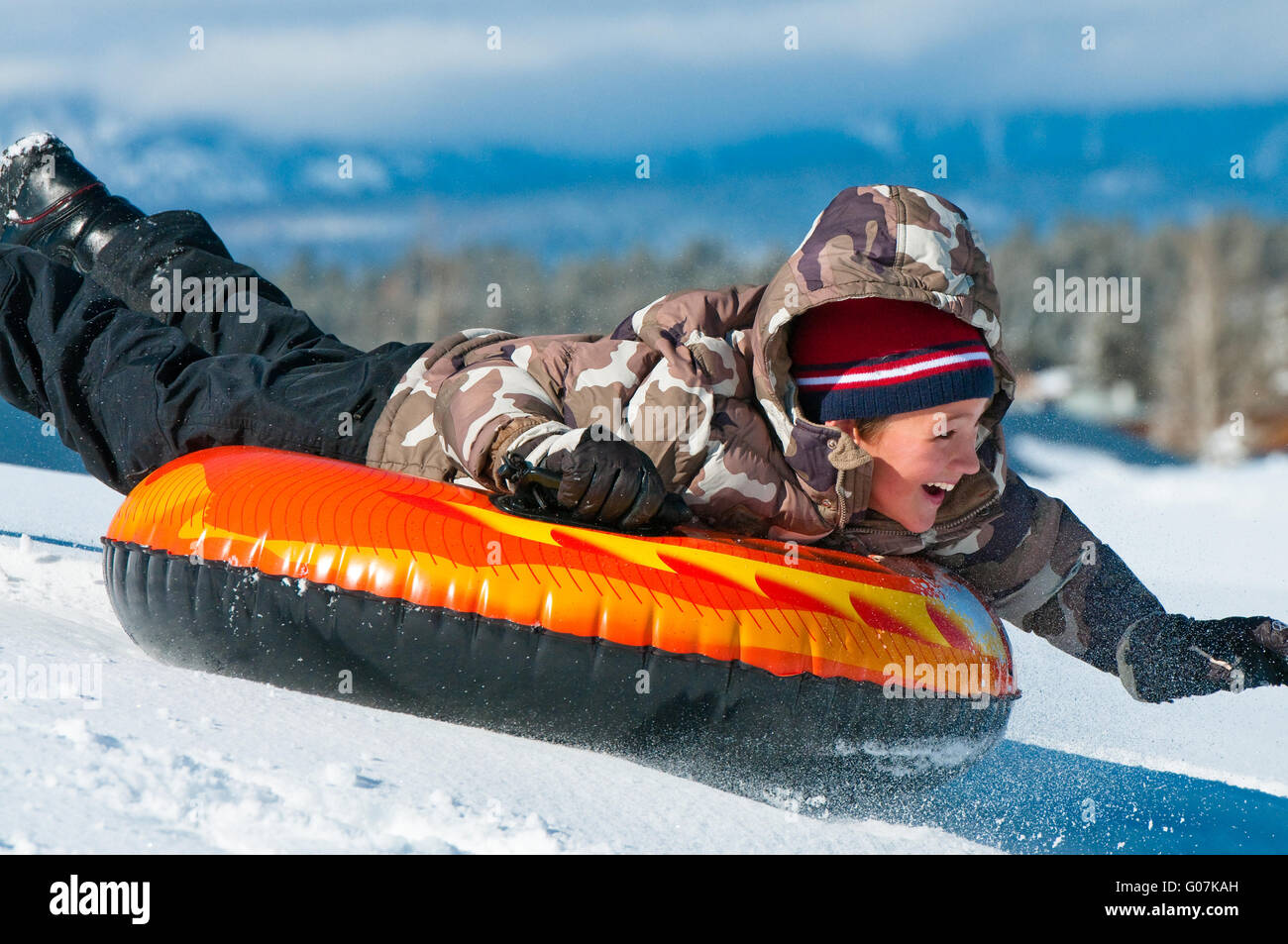 Fröhlicher Junge Reiten ein Rohr im Schnee Stockfoto