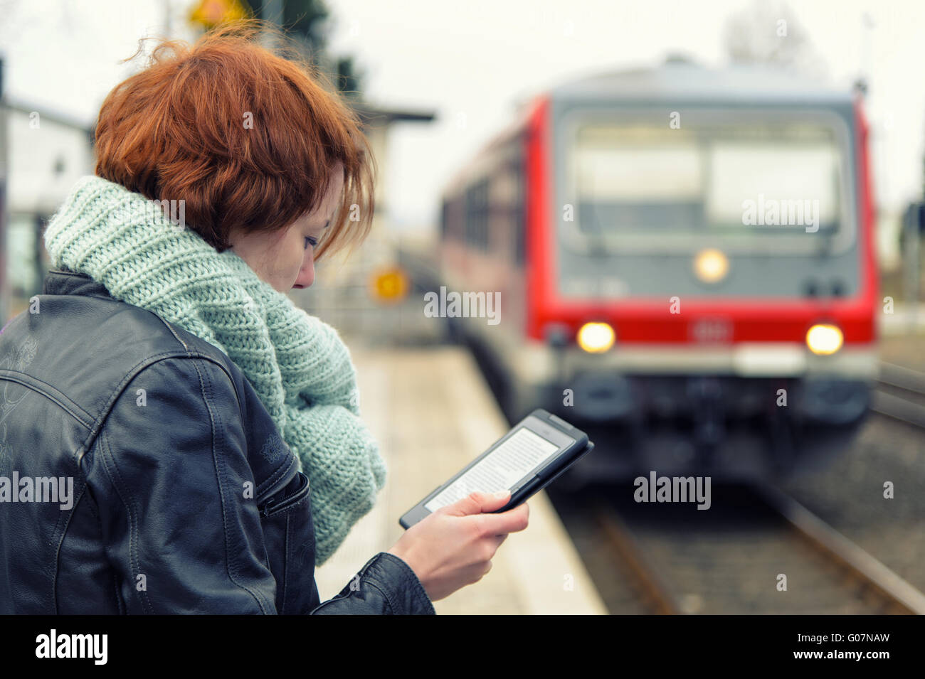 junge Frau liest ein eBook auf der Plattform mit Stockfoto