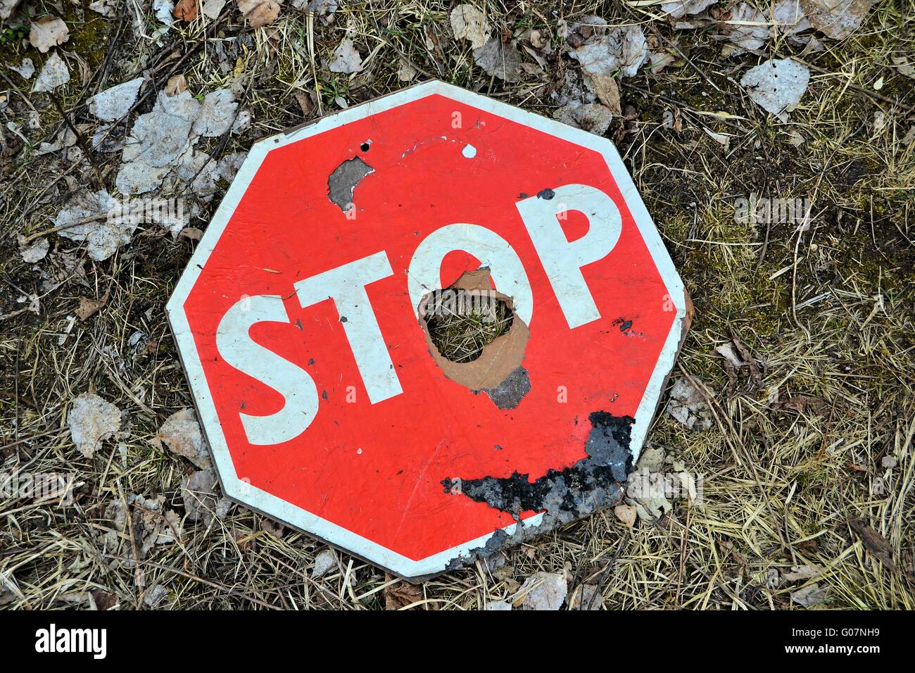 eine alte Stop-Schild mit einem Loch auf dem Boden gelegen Stockfoto