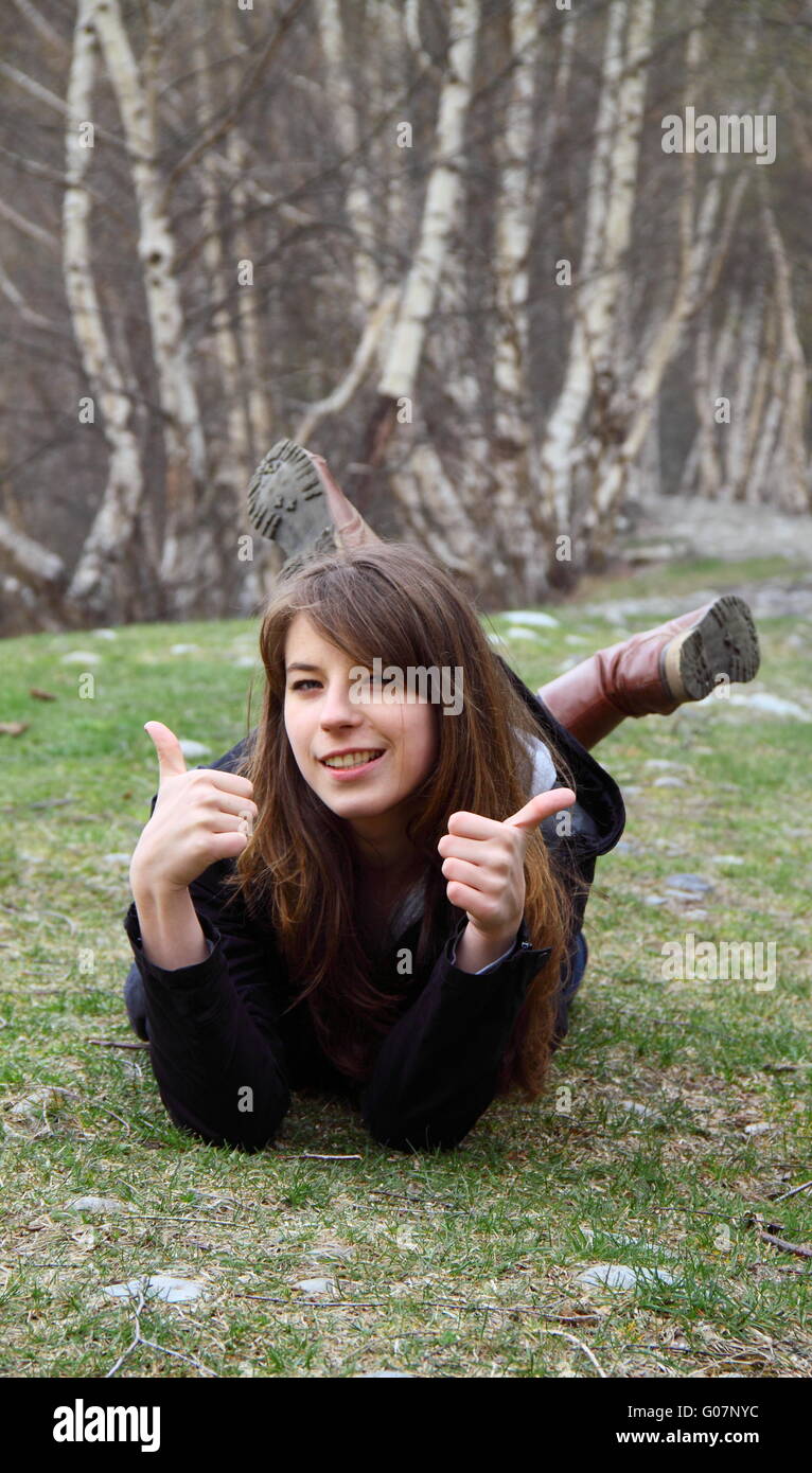 Junge schöne Mädchen liegen auf dem Rasen und zeigt Stockfoto