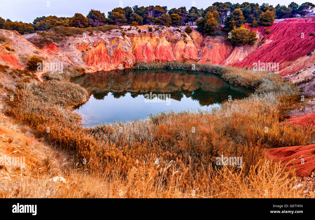 rote Böden rund um den See gebildet, in einem ehemaligen Steinbruch zur Gewinnung von Bauxit in Italien Stockfoto