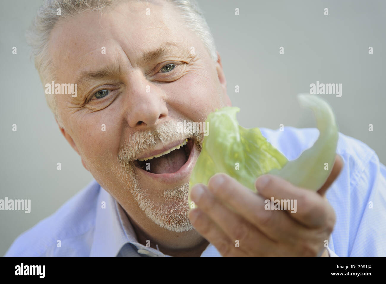 ein Senior isst genüsslich ein Stück Salat Stockfoto