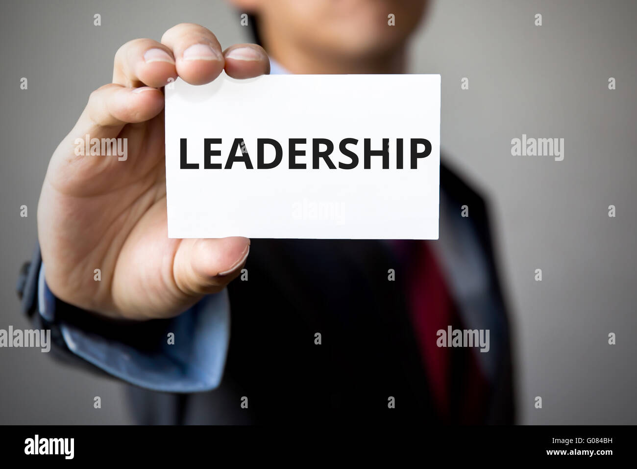 Geschäftsmann präsentiert "Leadership" Wort auf weißem Karton Stockfoto