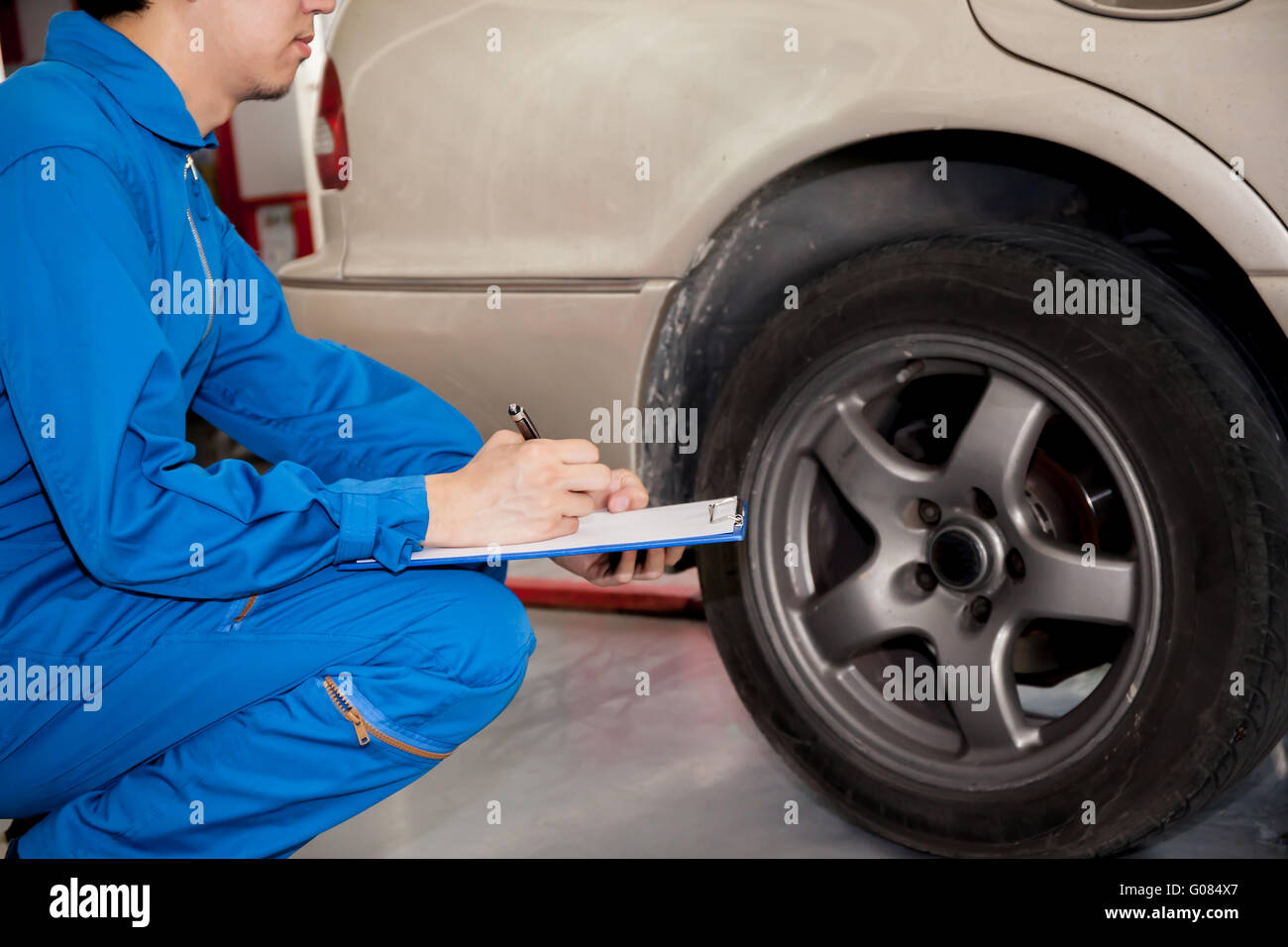 Junge Kfz Techniker Prüfung auf Pkw-Reifen in der Garage. Stockfoto