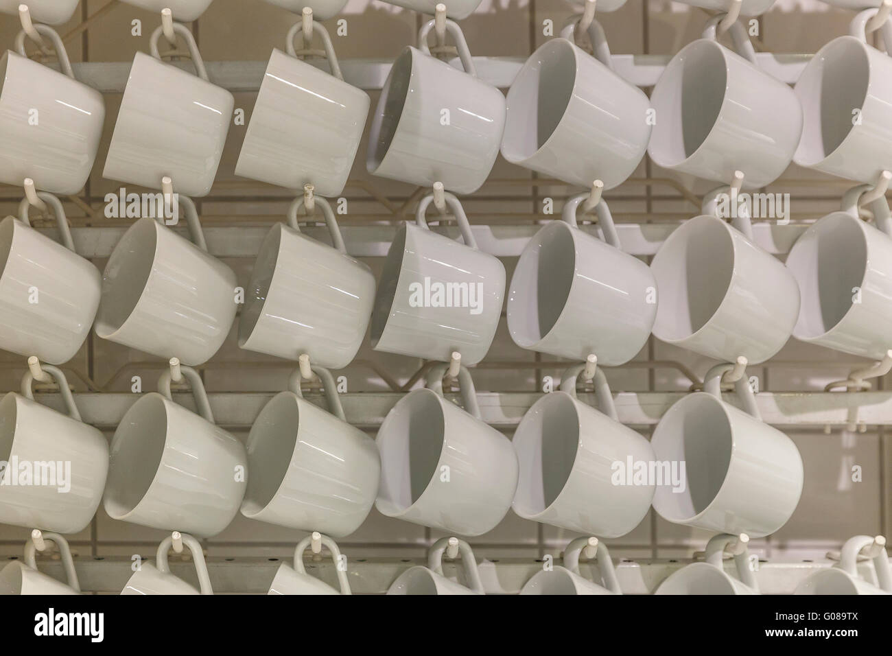 Weiße Tassen hängen an Haken im shop Stockfoto