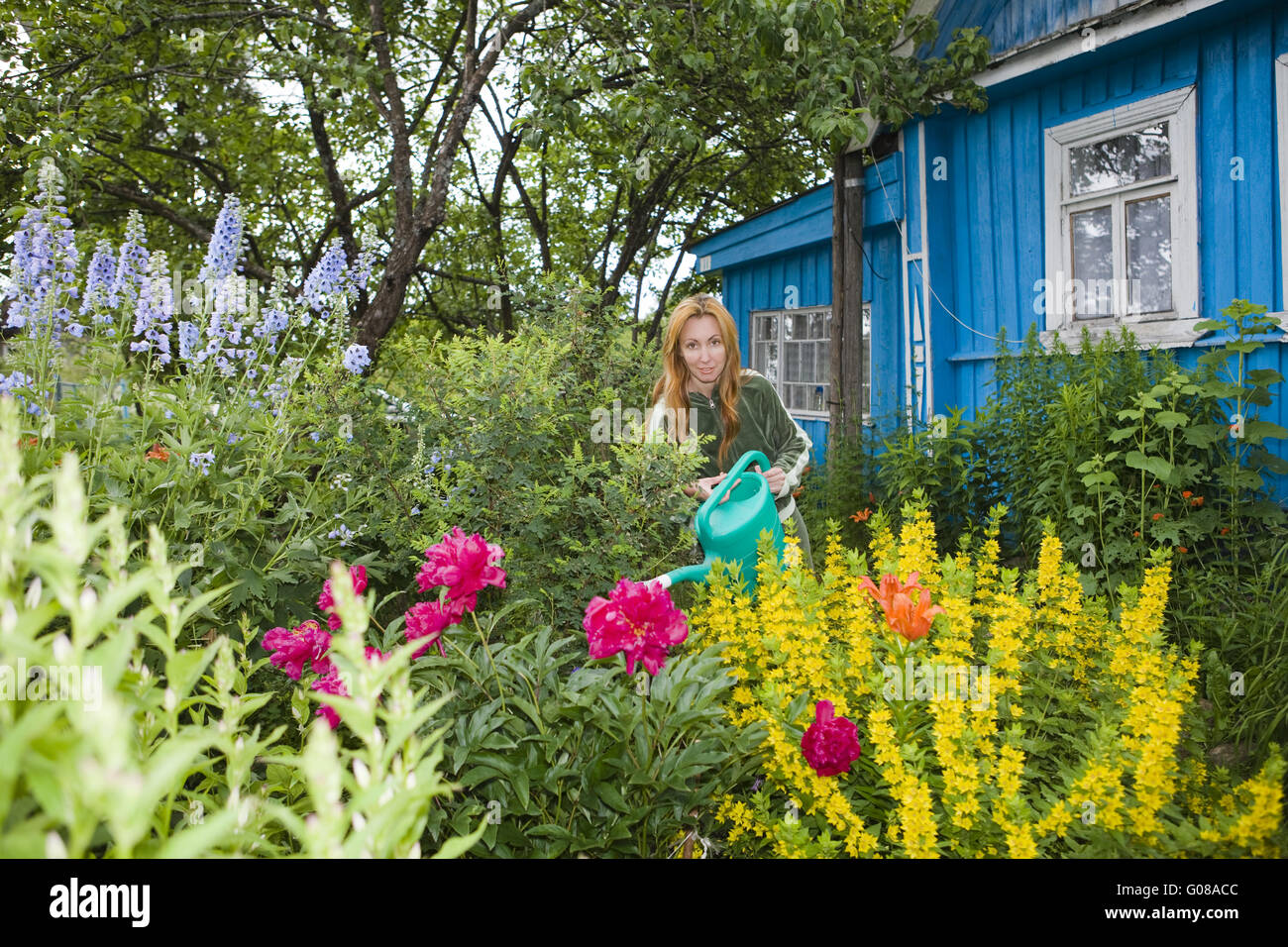 Junge hübsche Frau Wasser Blumen auf Garten-Grundstück Stockfoto