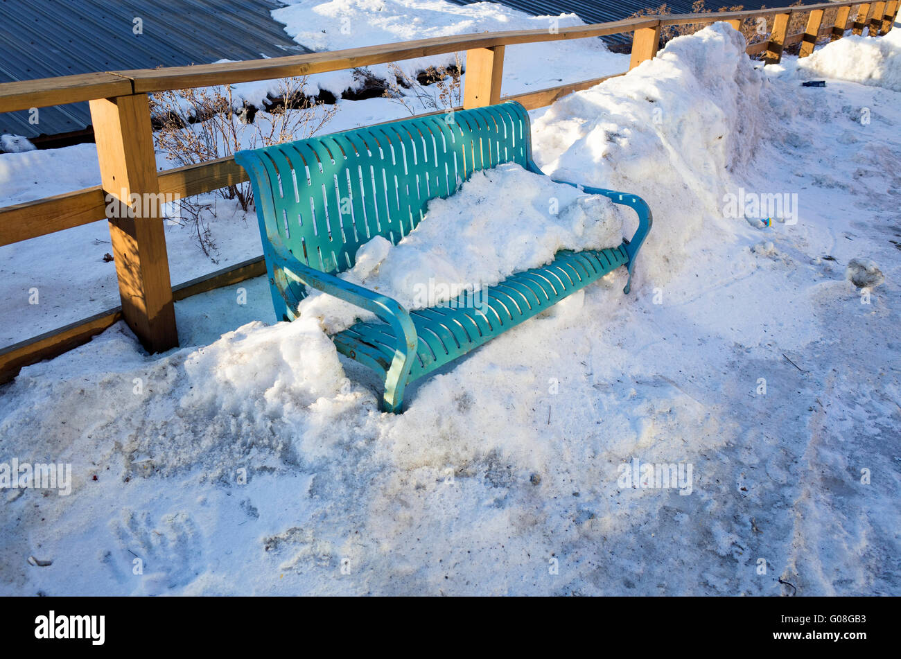 Schöne blau-grüne geschlitzte Sitzbank eingebettet in einer Schneewehe. Stillwater Minnesota MN USA Stockfoto