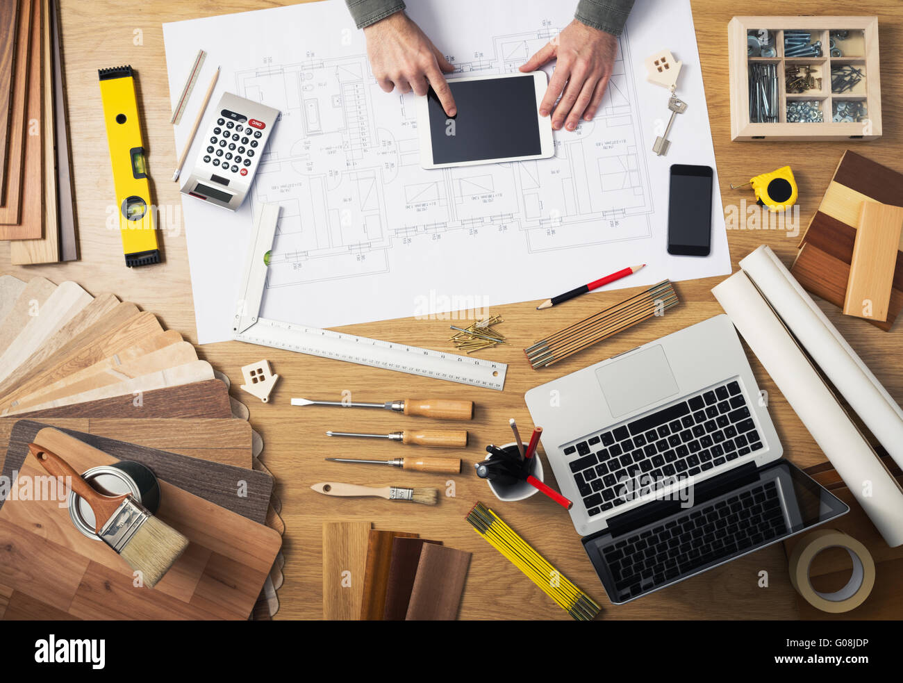 Bauingenieur und Architekt der Schreibtisch mit Hausprojekte, Laptop, Werkzeuge und Holz Farbfelder Draufsicht, Hände männlich mit einem Seitenhieb Stockfoto