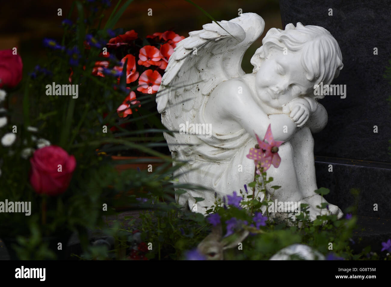 Weißer Marmor Engel zwischen Blumen und Figuren Stockfoto