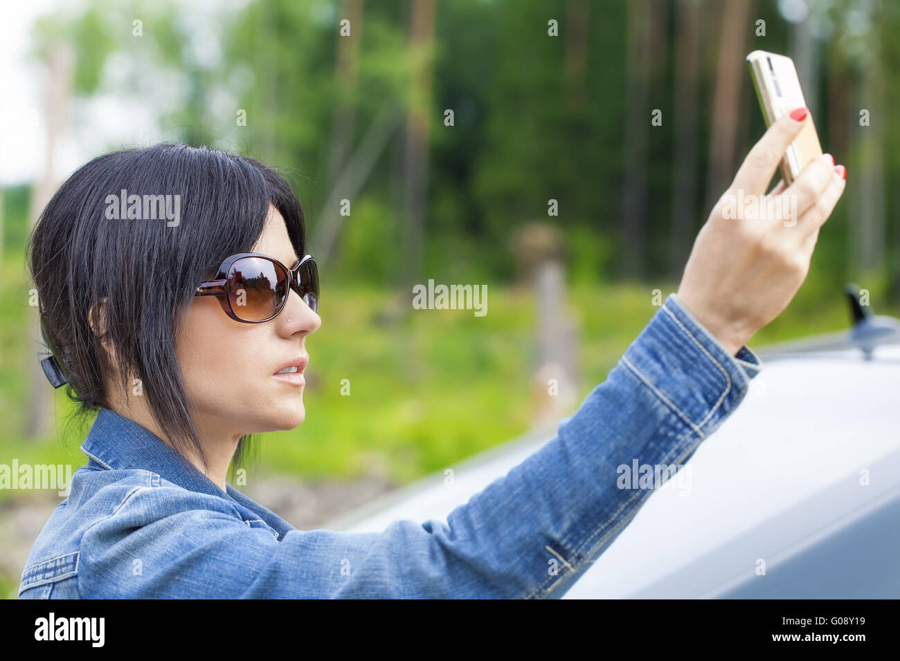 Frau mit Zelle Telefon auf der Straße in der Nähe von Auto Stockfoto