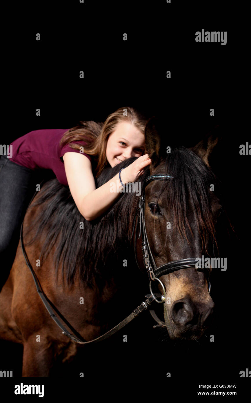 Mädchen und ihr Pony vor schwarzem Hintergrund Stockfoto