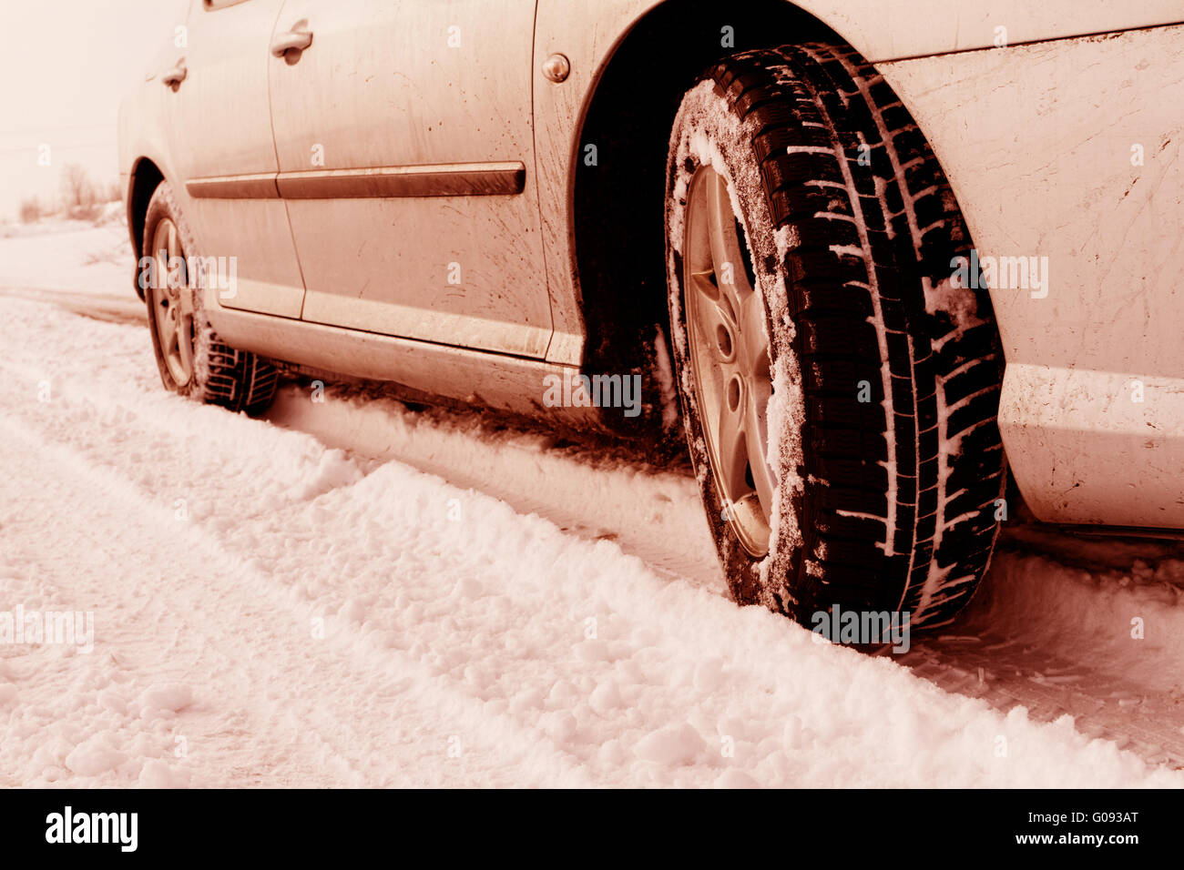 Nahaufnahme von Pkw-Reifen auf einer verschneiten Straße - Rot-Ton Stockfoto