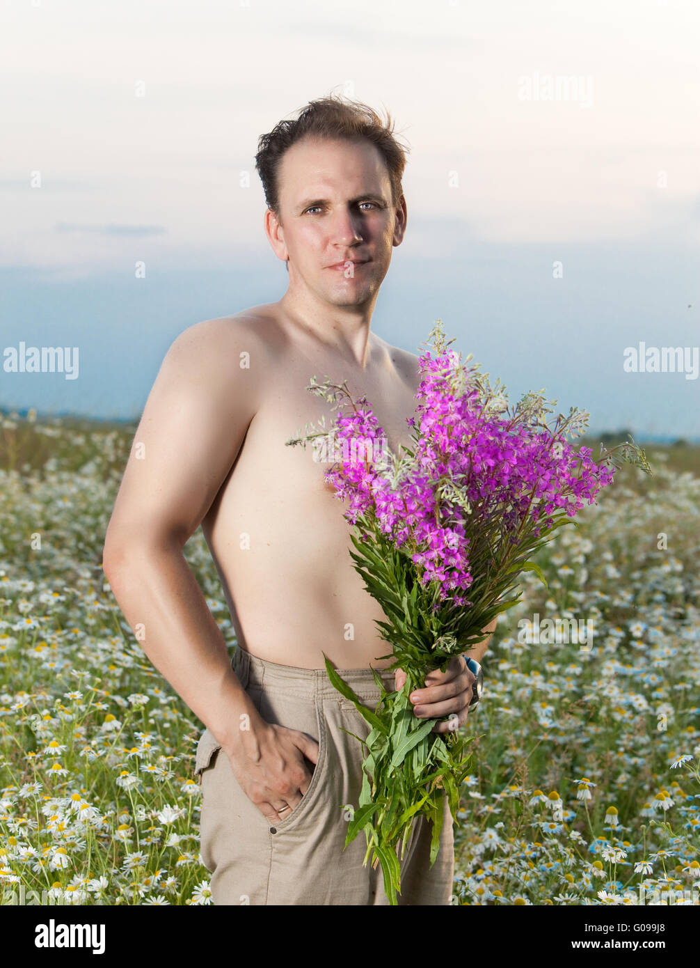 Dem lächelnden Mann, den ich im Feld mit einem Blumenstrauß Stockfoto