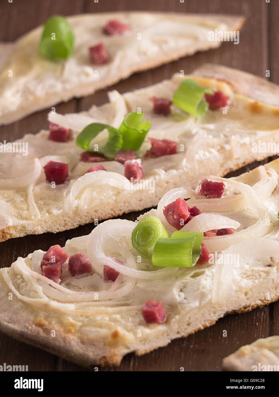 Tarte Flambée mit Zwiebeln und Schinken auf einem Holztablett Stockfoto