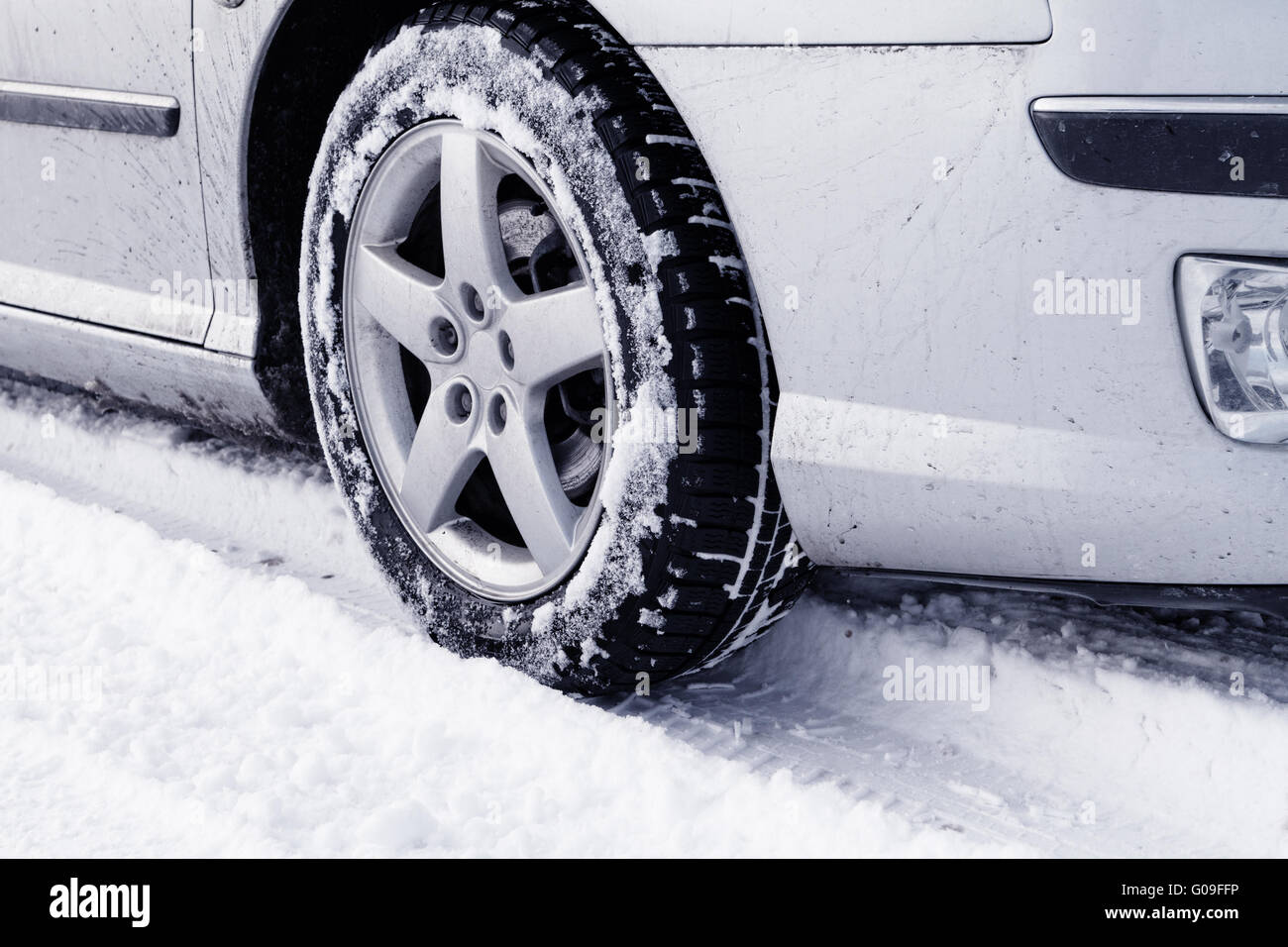 Nahaufnahme von Pkw-Reifen auf einer verschneiten Straße - Blauton Stockfoto