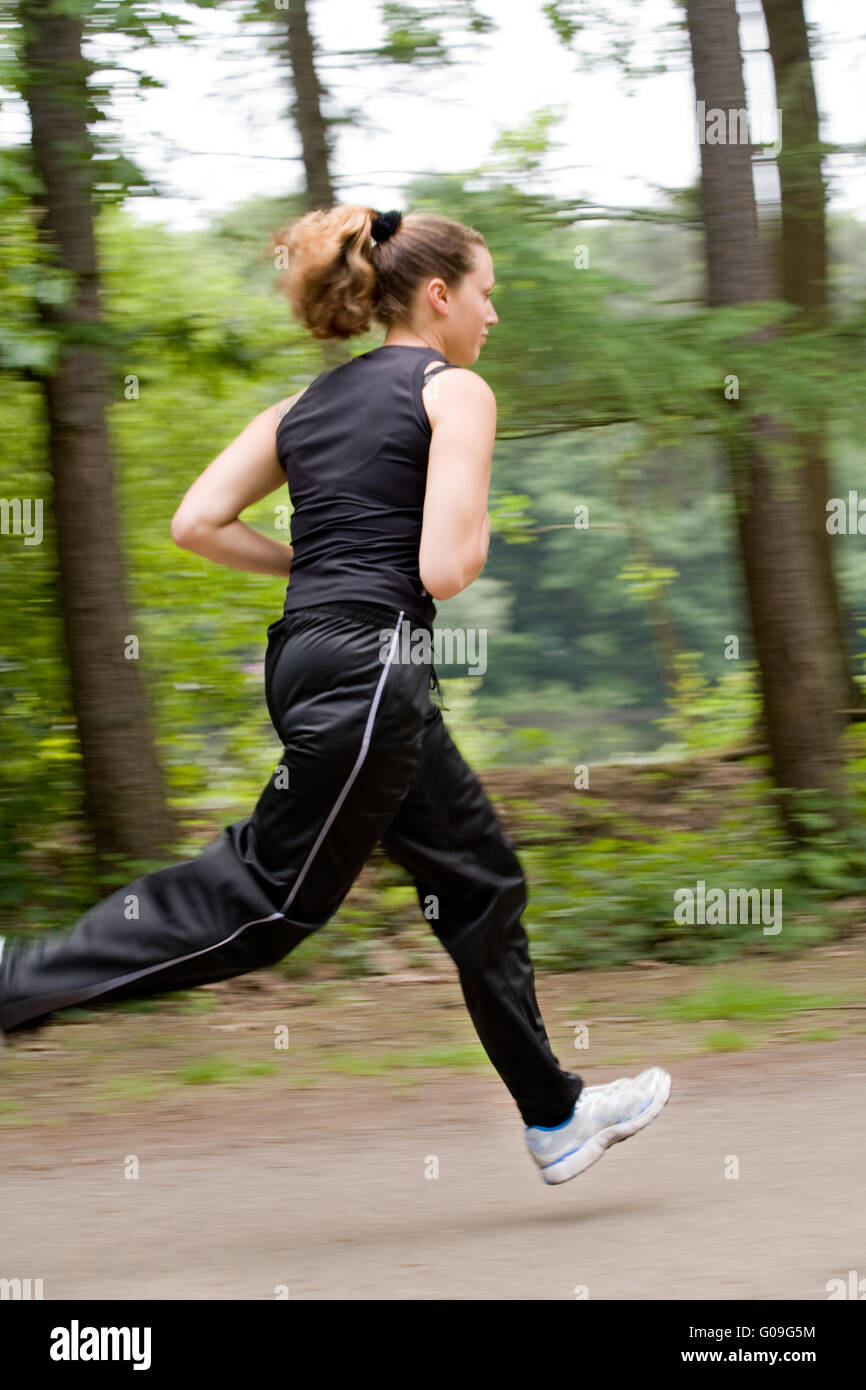 Sportliche junge Frau Überfahren einer Forrest-Straße Stockfoto