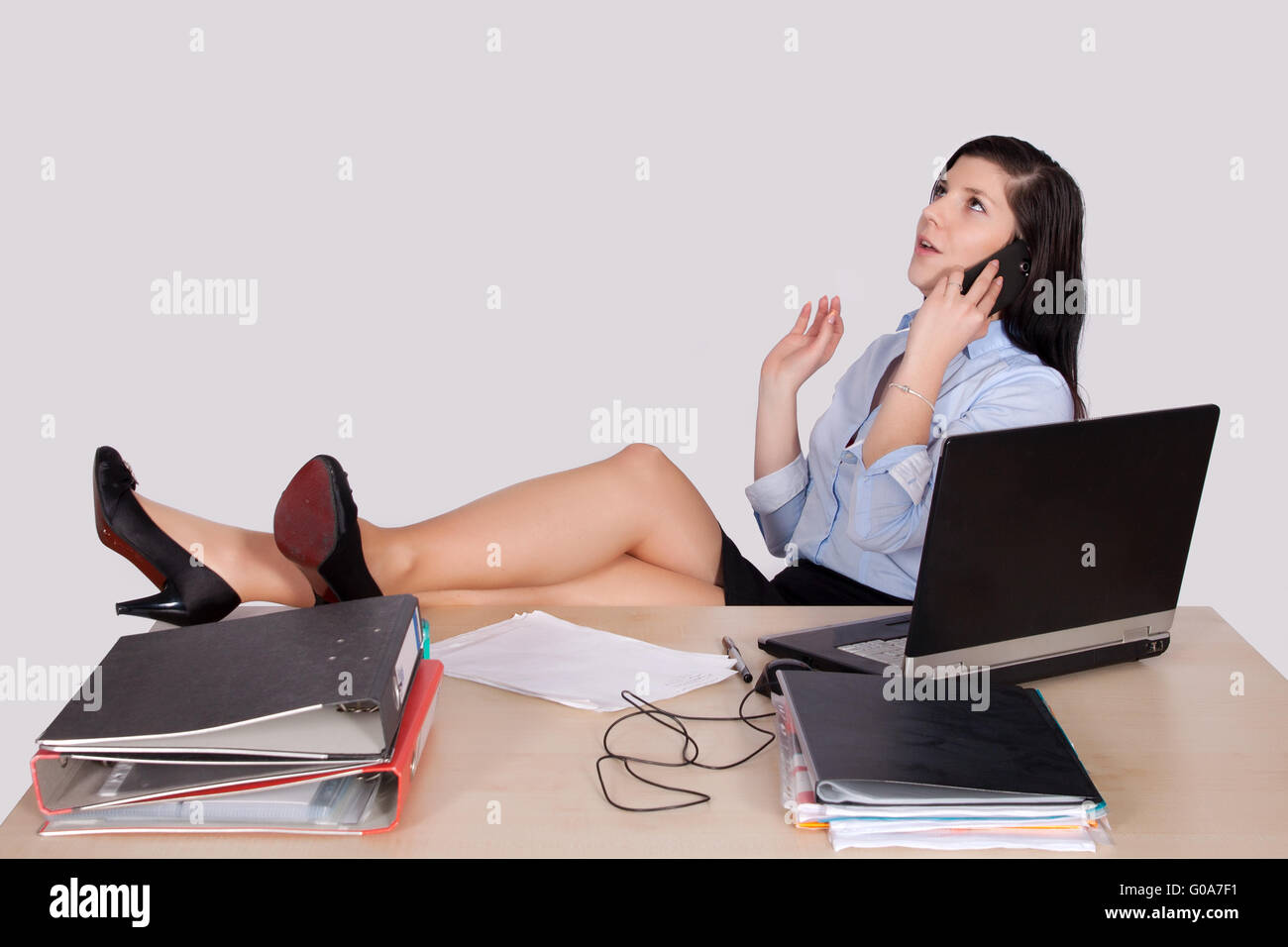 Junge weibliche Büroangestellte mit Füßen auf Schreibtisch Stockfoto