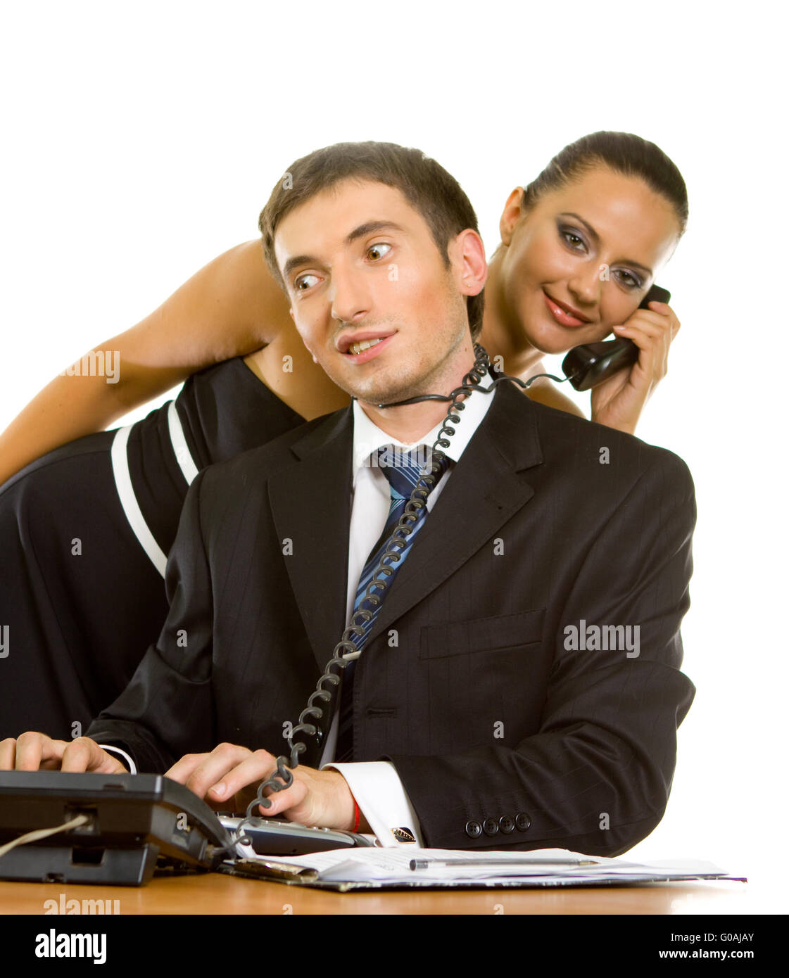 junger Geschäftsmann mit Telefon-Draht um den Hals auf einem Computer und eine junge Geschäftsfrau mit einem Telefonhörer am Pfingstmontag Stockfoto