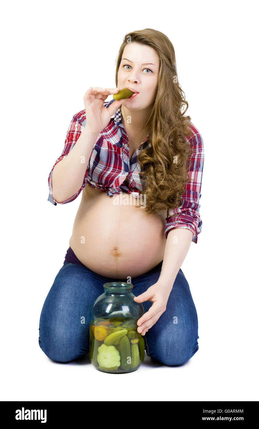 Schwangere junge Frau auf einem weißen Hintergrund frisst saure Gurken Stockfoto