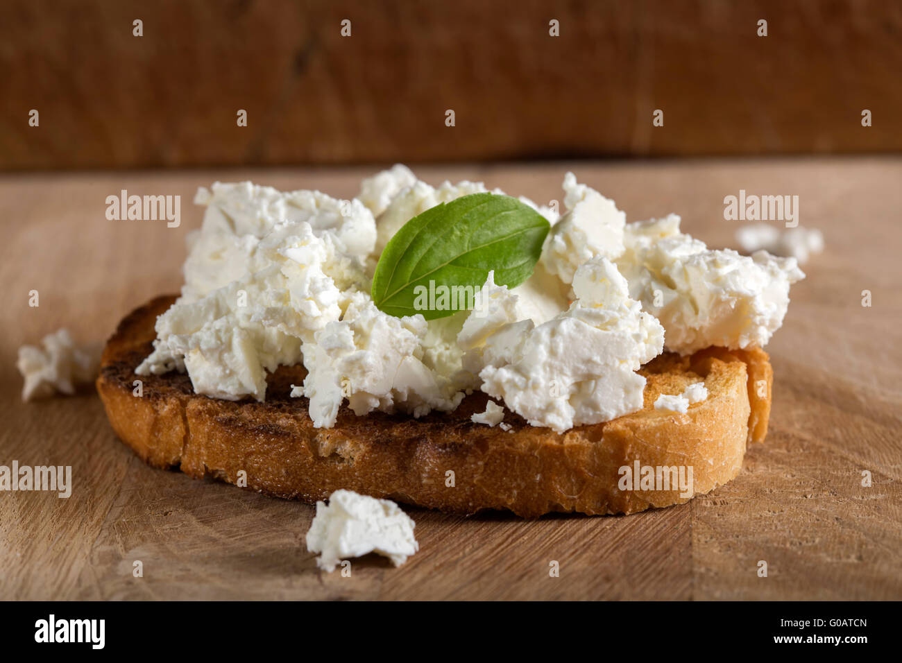 Roggen-Sandwiches oder Bruschetta mit Ricotta-Käse und Basilikum auf Holzbrett Stockfoto