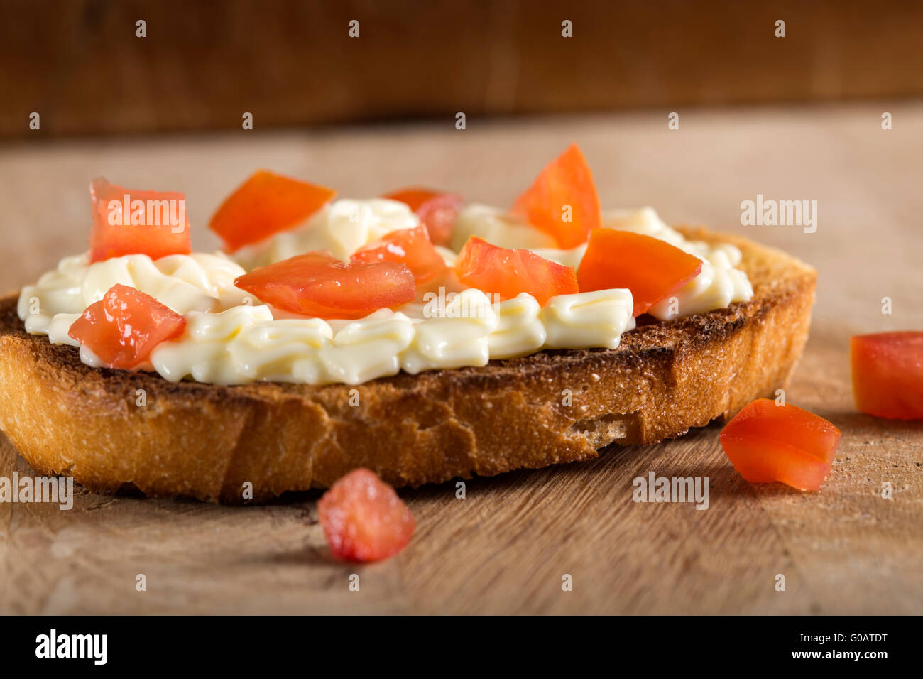 Käsecreme auf Toast mit Tomaten über hölzerne Hintergrund geschmolzen Stockfoto