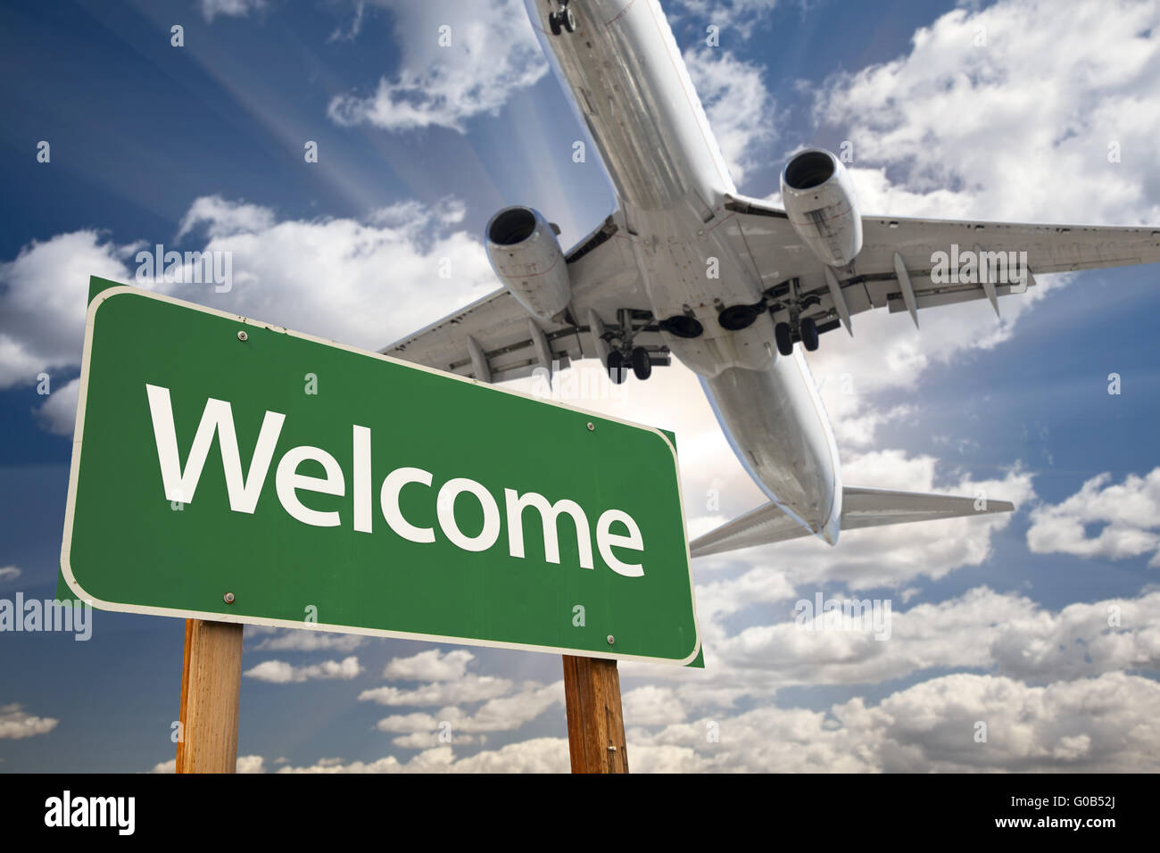 Grüne Verkehrszeichen und Flugzeug oben begrüßen Stockfoto