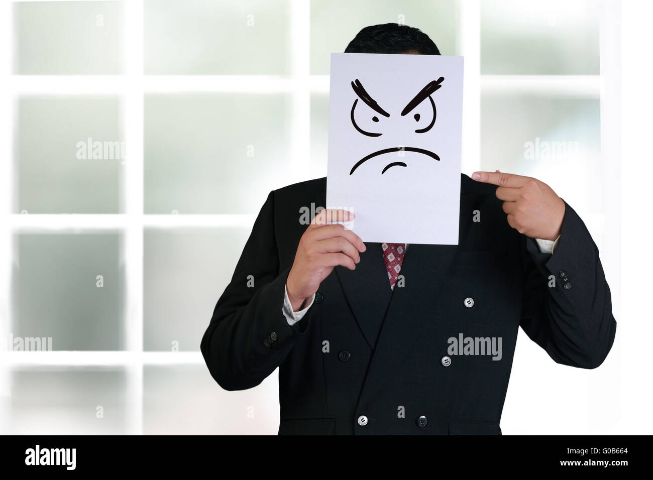 Firmen-Konzept-Image eines Geschäftsmannes halten und zeigen weiße Papier-Maske mit wütendes Gesicht drauf gezogen Stockfoto