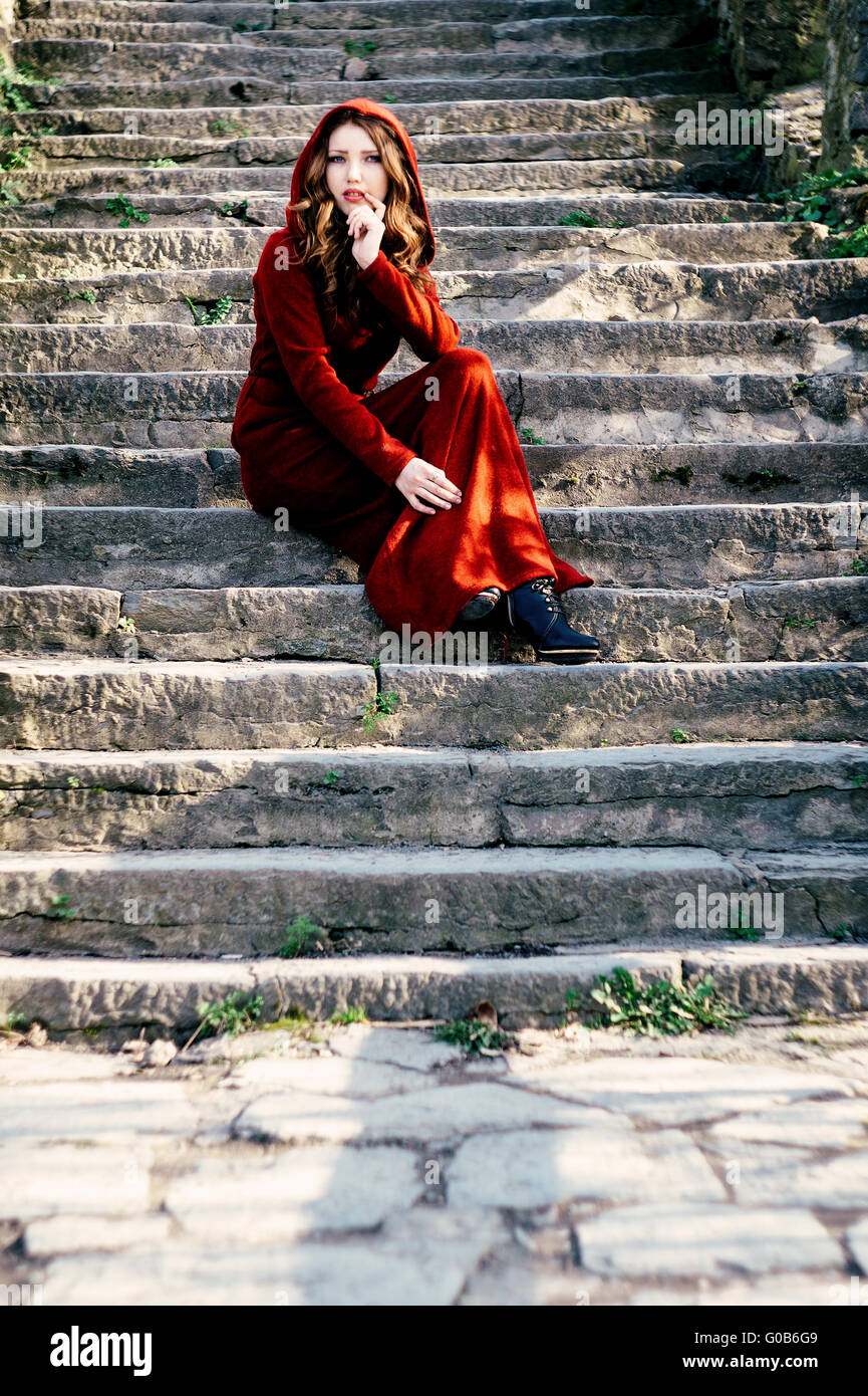 Schöne Frau im roten Kleid sitzt auf alten Schritte Stockfoto