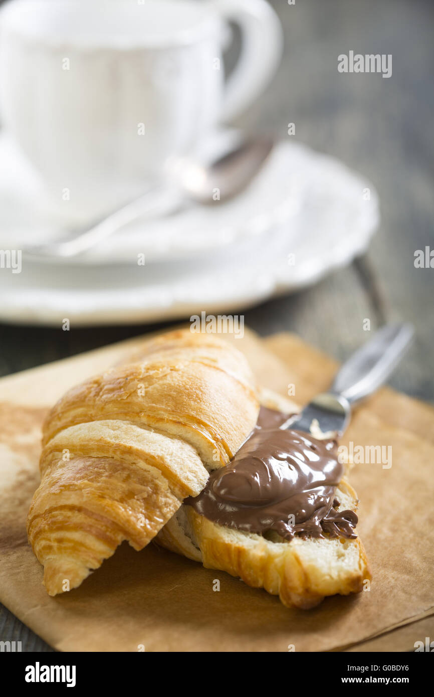 Croissant mit Schokolade auf einem Blatt Pergament. Stockfoto