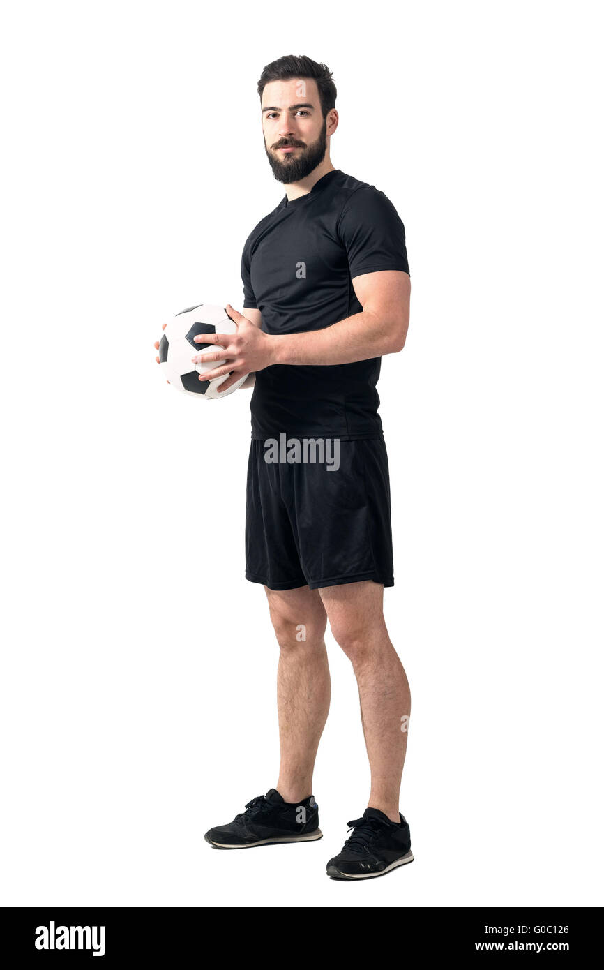 Zuversichtlich-Football-Spieler mit Ball mit beiden Händen, Blick in die Kamera. Ganzkörper-Länge-Porträt isoliert auf weißem Hintergrund Stockfoto