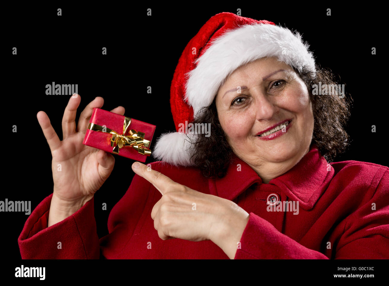 Fröhliche alte Dame zeigt auf rot Weihnachtsgeschenk Stockfoto