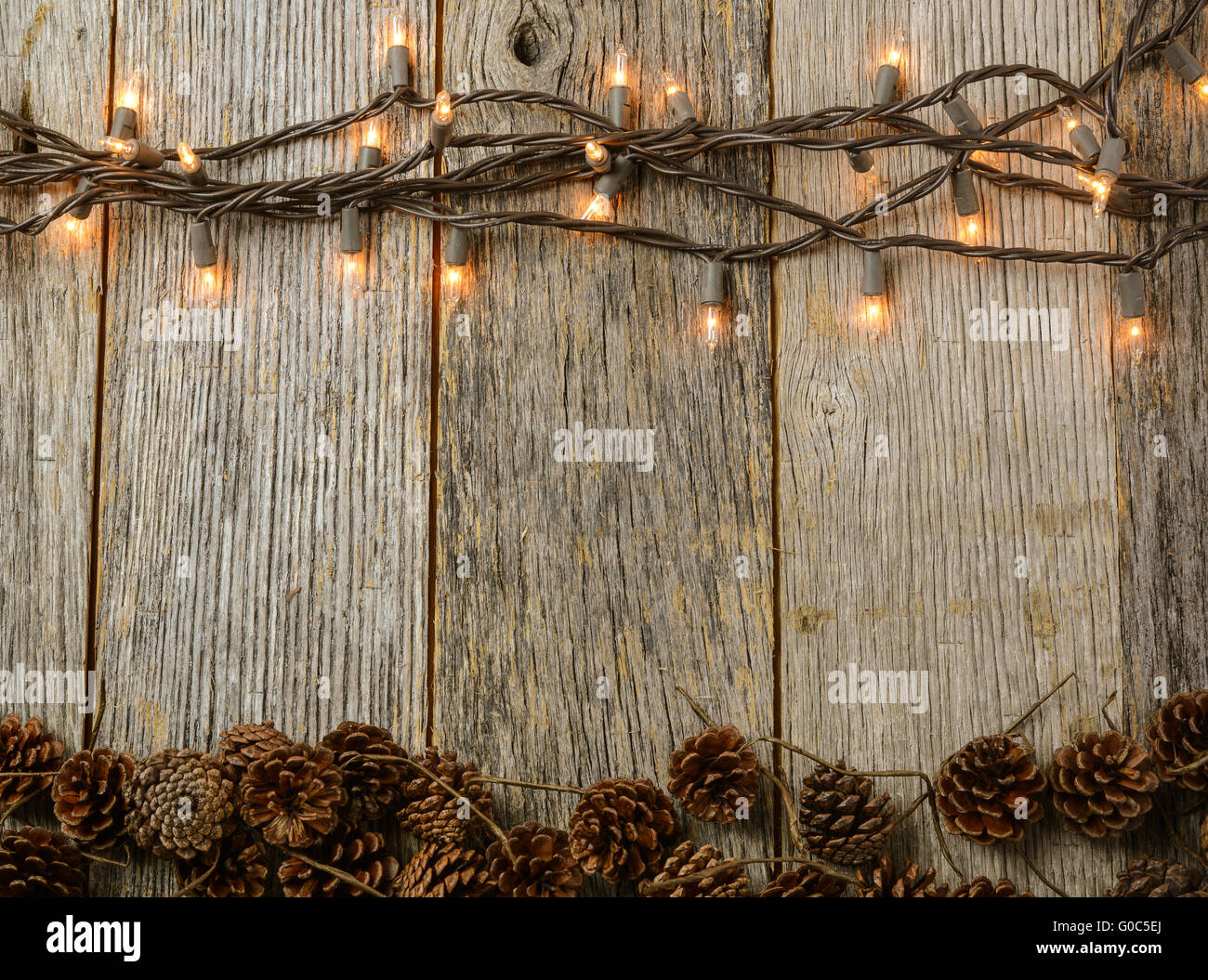 Weihnachtsbeleuchtung und Kiefer Kegel auf rustikalen Holz-Hintergrund Stockfoto