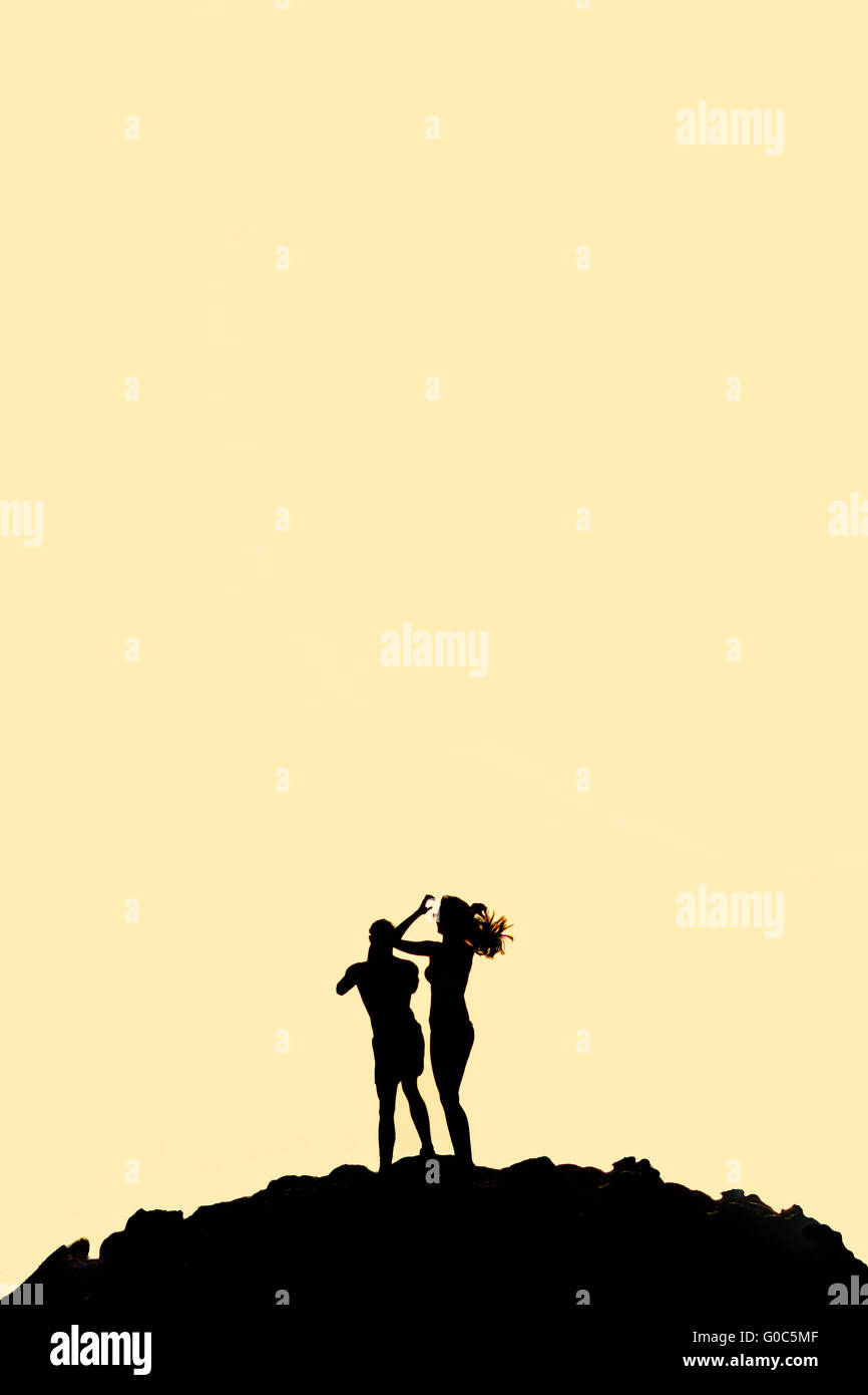 Mann und Frau stehen auf Bergsilhouette Stockfoto